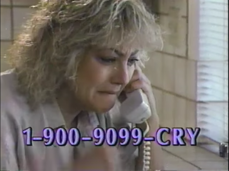 Advert for 1-900-9099-CRY. A woman cries at her phone in the kitchen.